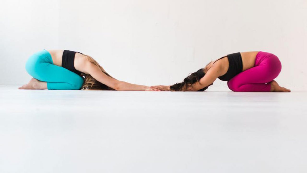 Full body side view of sporty couple in activewear performing yoga pose  while he is lying down with his legs stretched out and she is lying on his  fee Stock Photo -